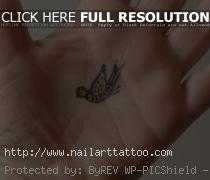 Tiny tattoo of a paisley bird in the palm of the hand. Small tattoos